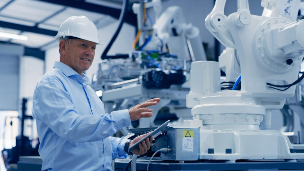 Machine, testing tablet and man working on engineer, electronic technician and robotics. Mature male employee, tech and factory engineering job of worker checking robot mechanics and automation